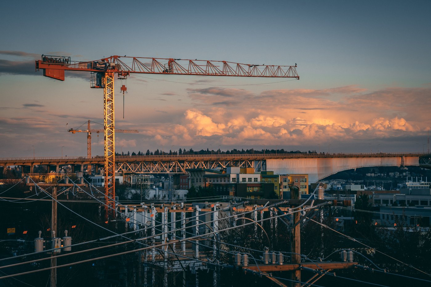 Construction crane silhouetted against the sky at sunset over a job site