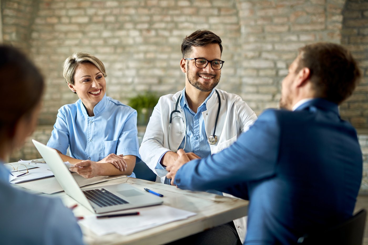 Care team meeting with a patient around a laptop and clipboard